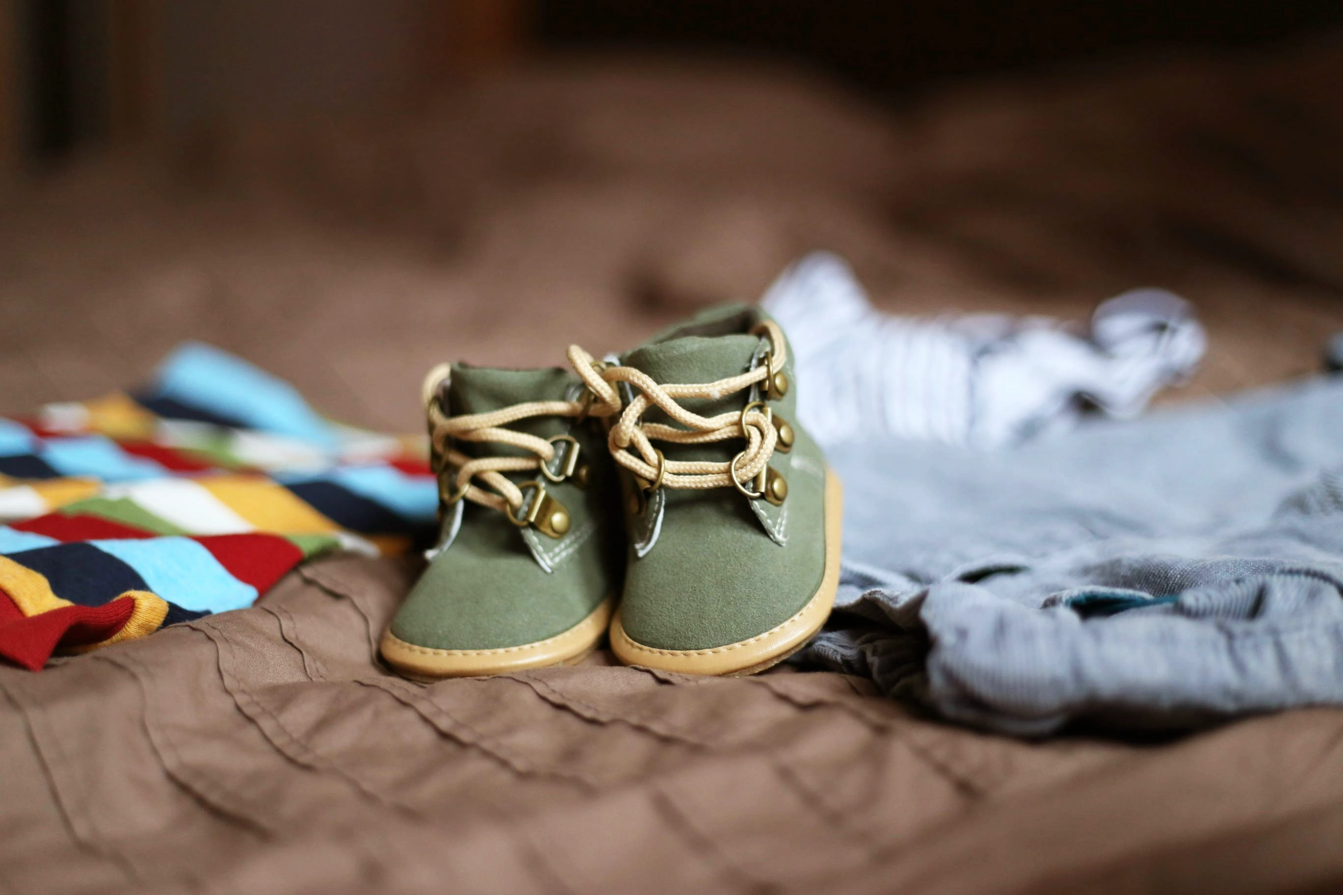 Tiny baby shoes and clothes laid out on a bed, representing family life