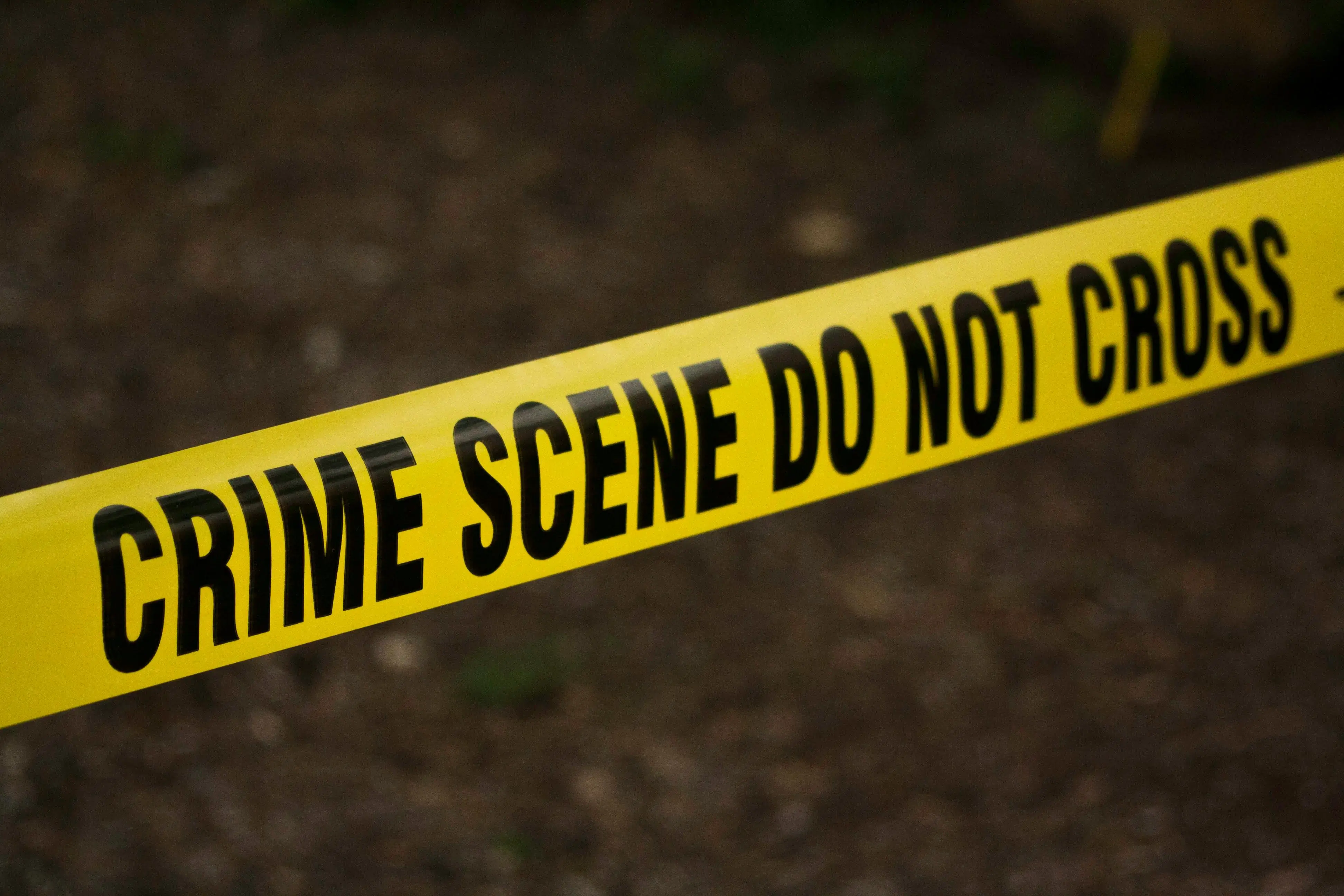 Close-up of yellow crime scene tape reading 'CRIME SCENE DO NOT CROSS'