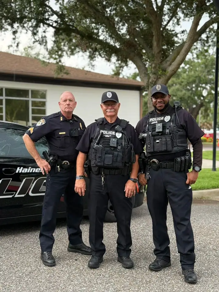 Three Haines Police officers standing together by their patrol vehicle