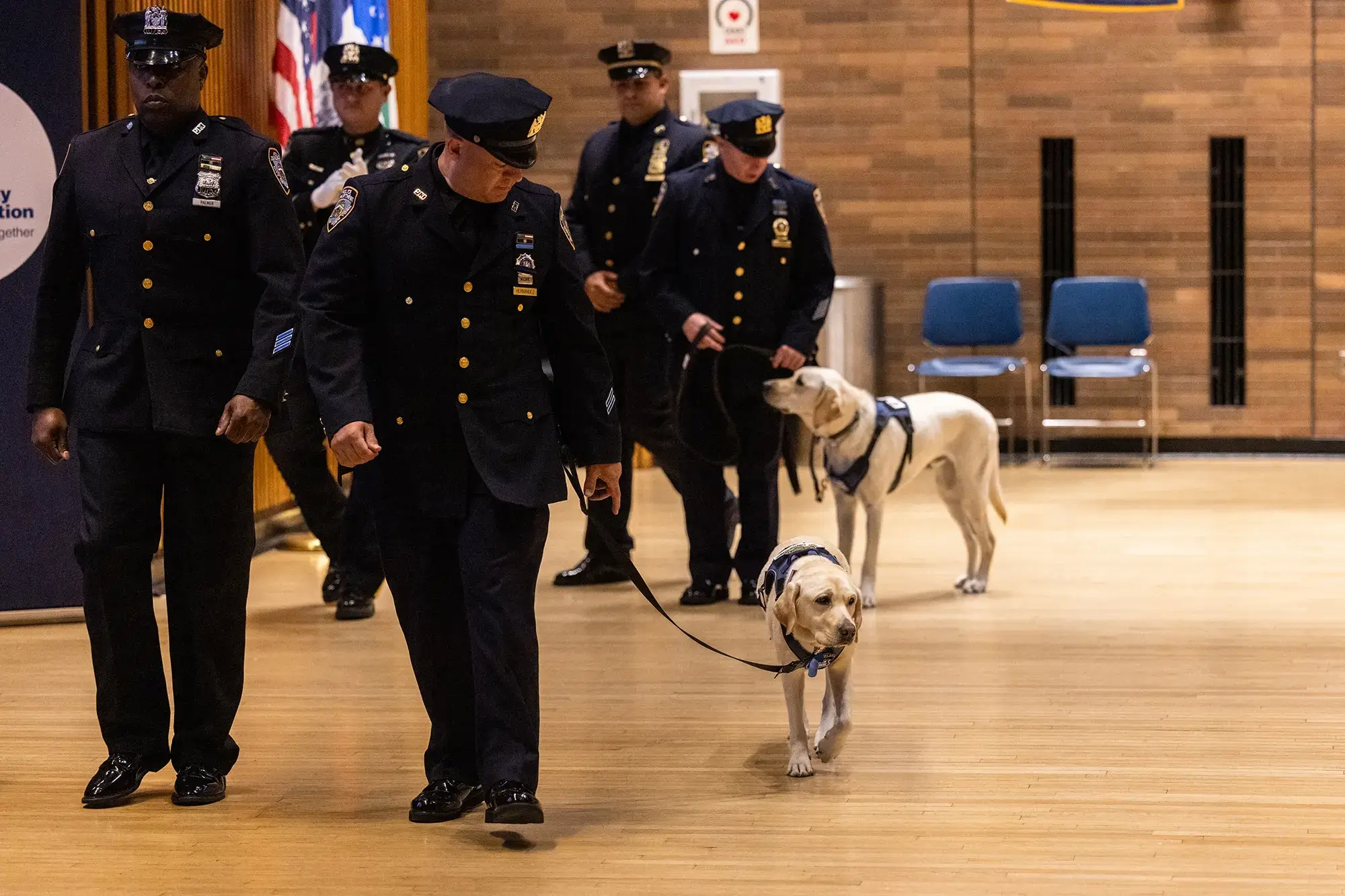 NYPD officers in dress uniforms with an emotional support dog at a formal ceremony
