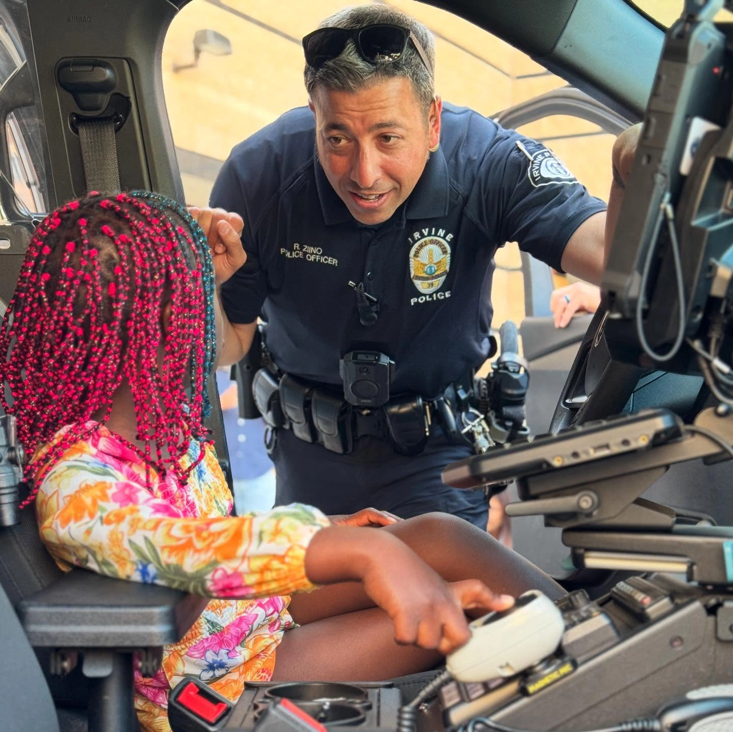 Irving Police Officer showing a young child the inside of a police vehicle during a community engagement event