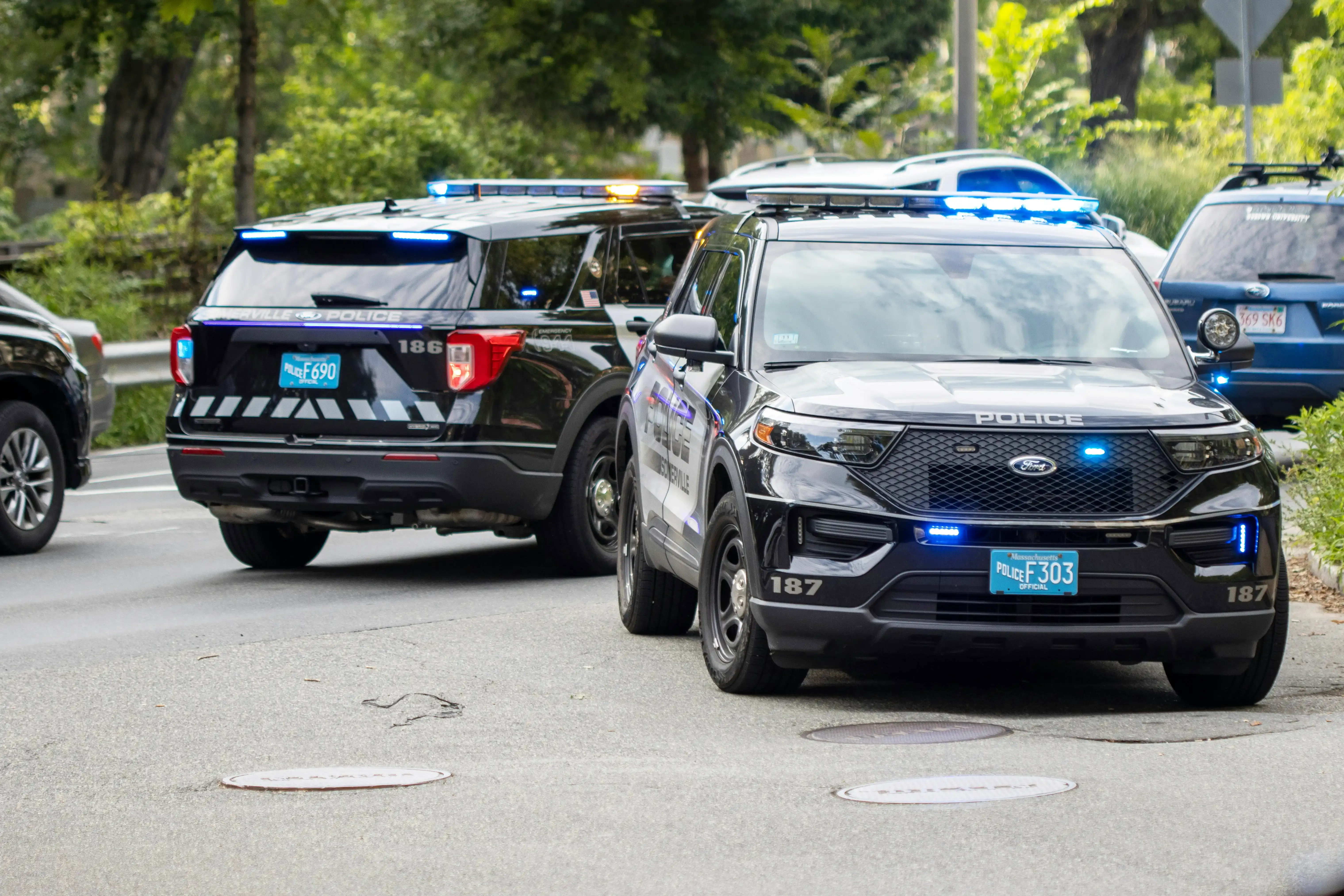 Multiple police patrol vehicles with emergency lights activated responding to a call